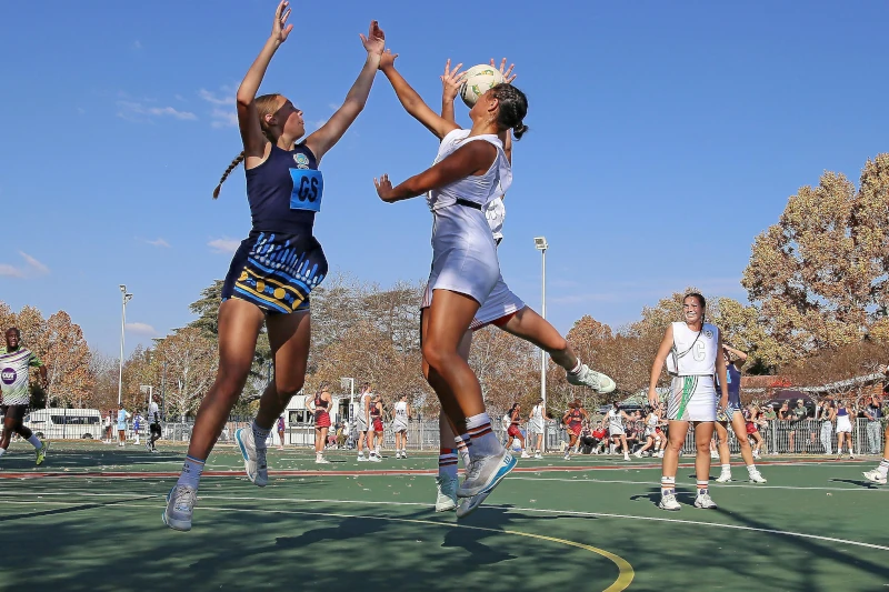 A woman attempting to score in a netball game outside